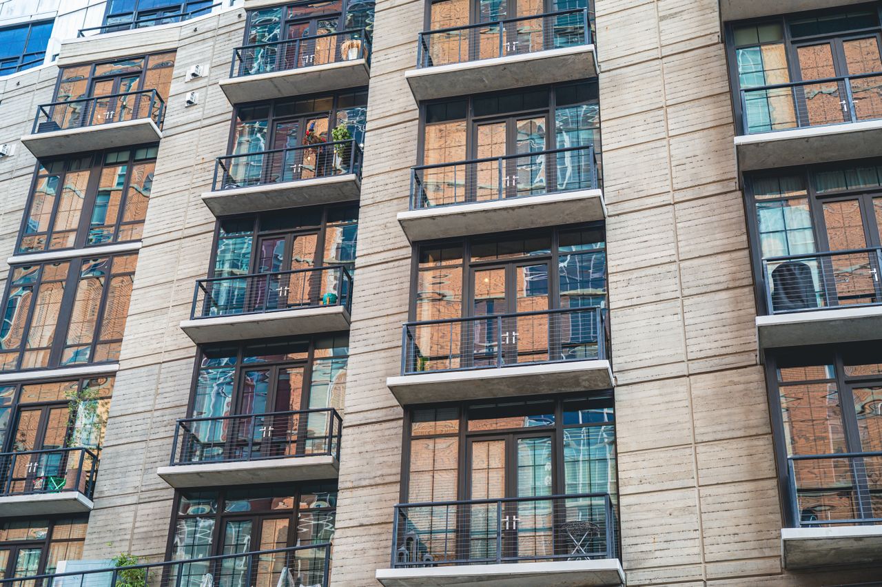gallery-img-05 Contemporary apartment building exterior with concrete facade and glass balconies.