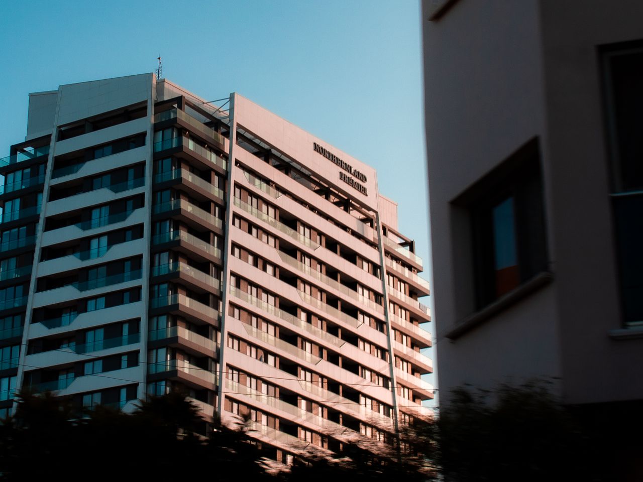 programs-02 Low angle view of a modern apartment building with balconies, captured during sunset.