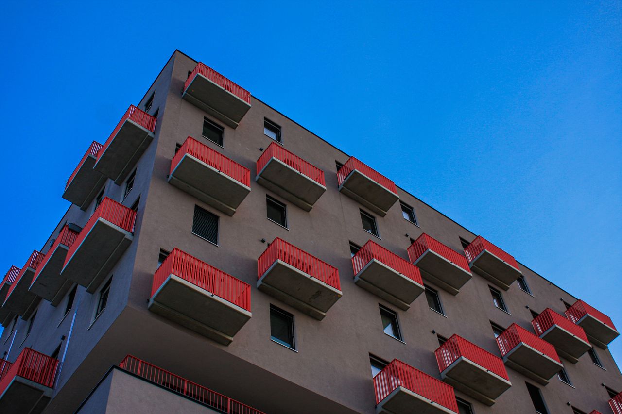 The Art of Drawing Readers In: Your attractive post title goes here Low-angle view of a Vienna residential building with red balconies against a clear blue sky.